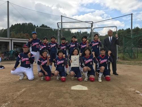 グラウンドで笑顔でガッツポーズをする篠山中学校ソフトボール部の写真